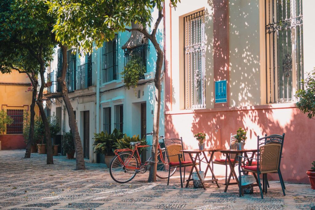 Piazza del quartiere di San Bartolomé a Siviglia, con case colorate, piante, tavolini e bici