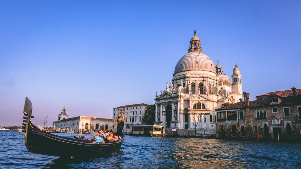 Una gondola attraversa i canali di Venezia al tramonto