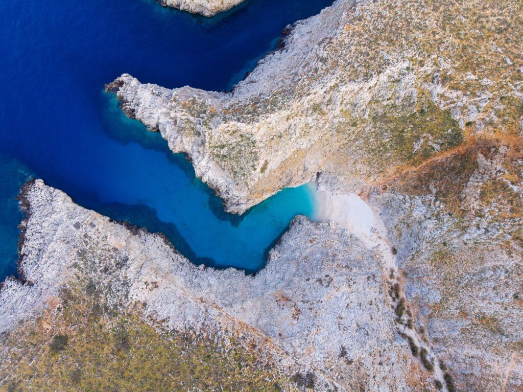 Vista dall'alto della stretta lingua di terra incastonata fra due alte pareti rocciose di Seitan Limania