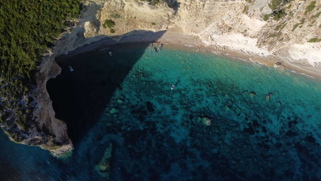 scogliere bianche e arbusti verdi si affacciano sul mare azzurro di Corfù