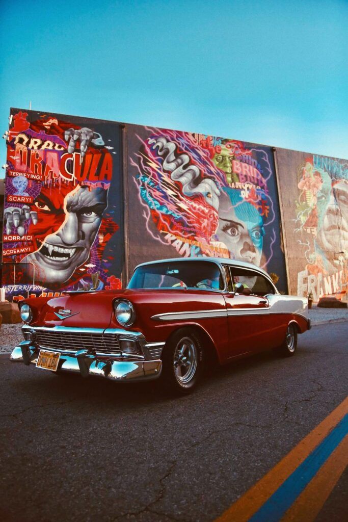 Un'auto rossa parcheggiata negli Universal Studios con dei murales sullo sfondo