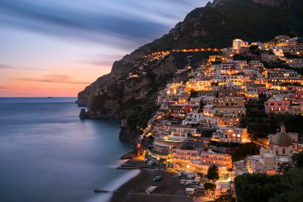 Le luci delle case di Positano sulla scogliera a picco sul mare al crepuscolo