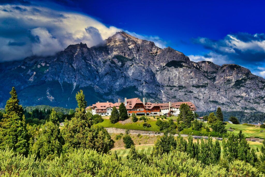 Edifici con il tetto rosso circondati dal verde e alle spalle le montagne dell'Argentina