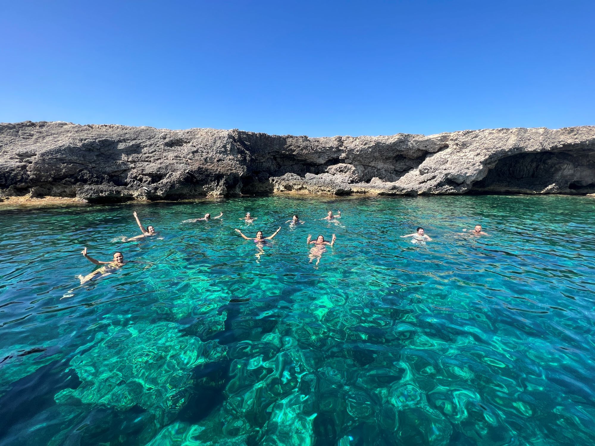 Persone fanno il bagno nelle acque turchesi di Lampedusa