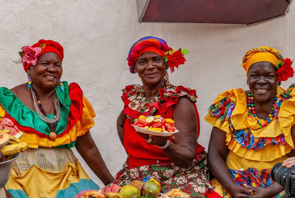 Palenquera a Cartagena con abiti tradizionali e frutta tropicale: icona vivente della cultura afrocolombiana e dei colori caraibici della Colombia.