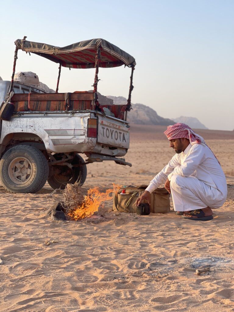 Uomo beduino accanto a un fuoco nel deserto Wadi Rum