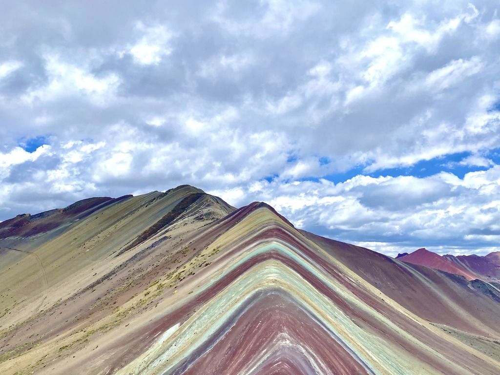 Vista panoramica della Vinicunca, la montagna colorata del Perù, con le sue striature naturali sotto un cielo nuvoloso.