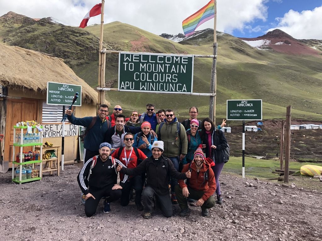 Gruppo di escursionisti davanti al cartello di benvenuto alla Vinicunca, inizio del trekking verso le montagne colorate del Perù.