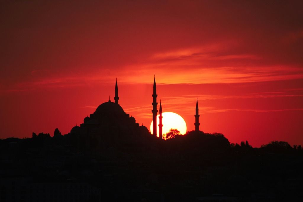 Silhouette di una moschea di Istanbul stagliata su un cielo rosso intenso al tramonto.