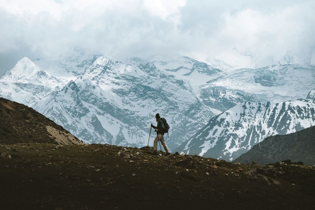 Escursionista su un sentiero di montagna con le vette innevate dell’Himalaya sullo sfondo.
