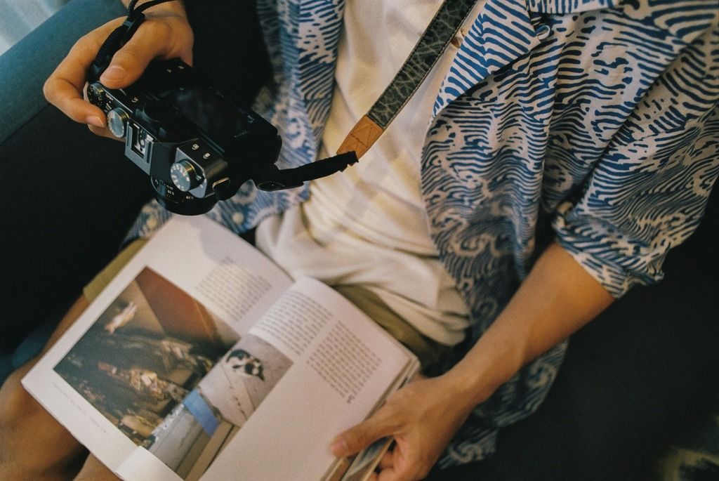 Primo piano di una persona che sfoglia un libro illustrato, con una macchina fotografica in mano.