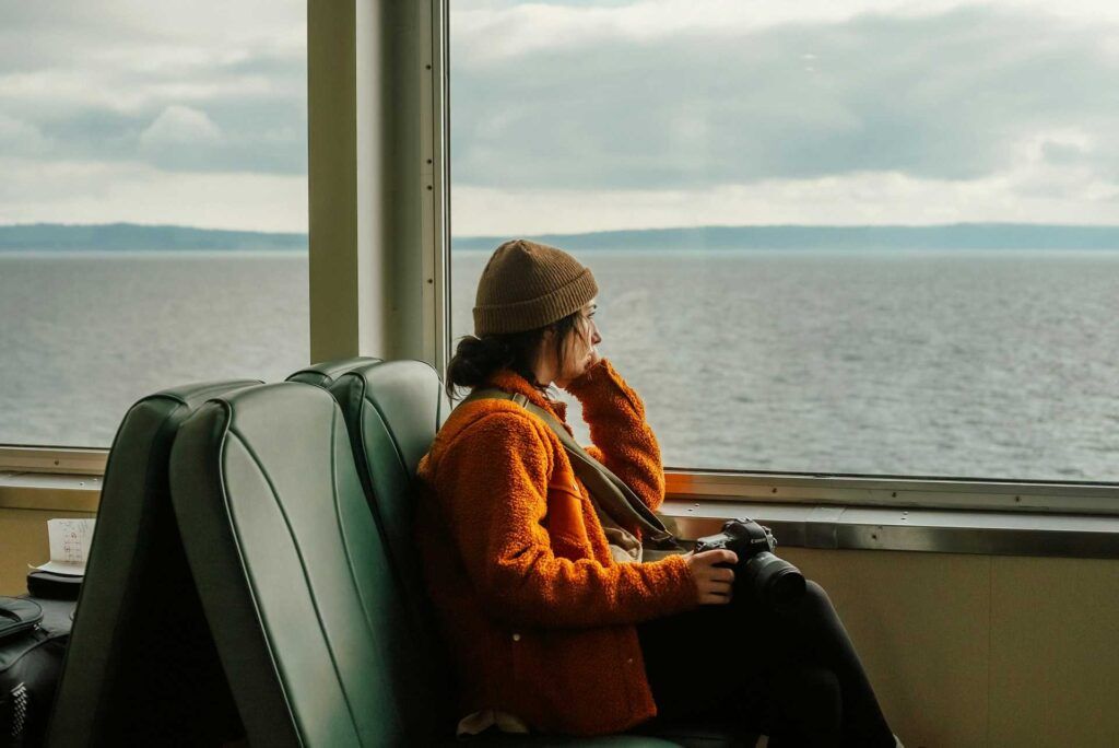 Ragazza con depressione da rientro, guarda malinconicamente dalla finestra di un traghetto.