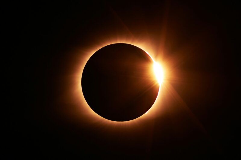 Eclissi solare totale con effetto diamond ring: la corona solare illumina il bordo della luna su sfondo nero