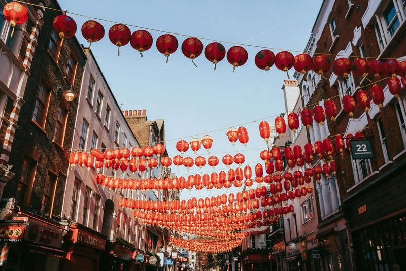 Strada di un quartiere cinese decorata con file di lanterne rosse sospese tra gli edifici