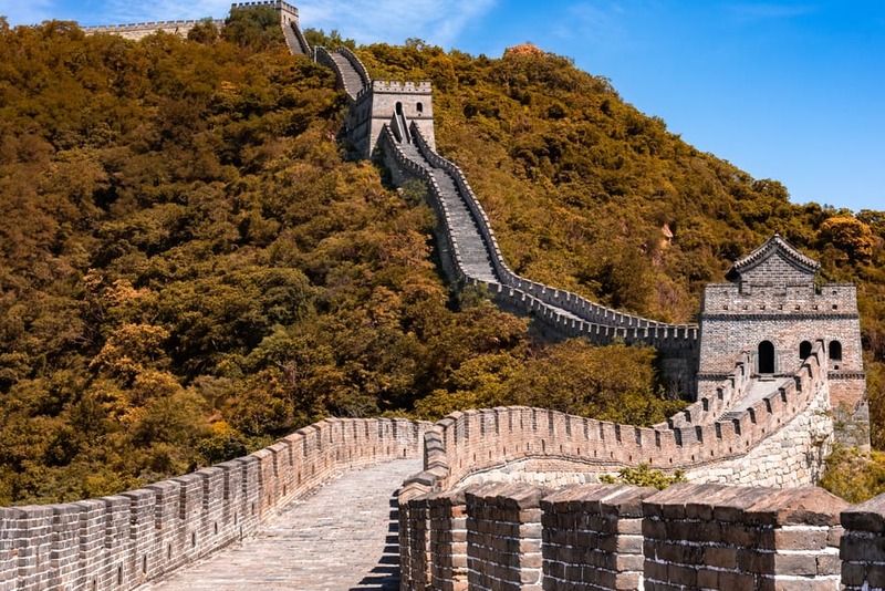 Tratto della Muraglia Cinese con torri di sorveglianza e camminamento in pietra sotto un cielo azzurro