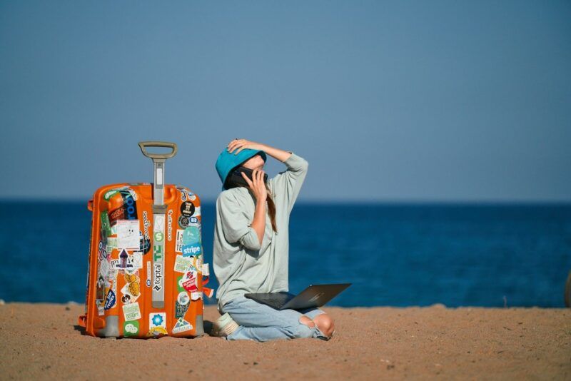 Ragazza seduta con valigia da viaggio.
