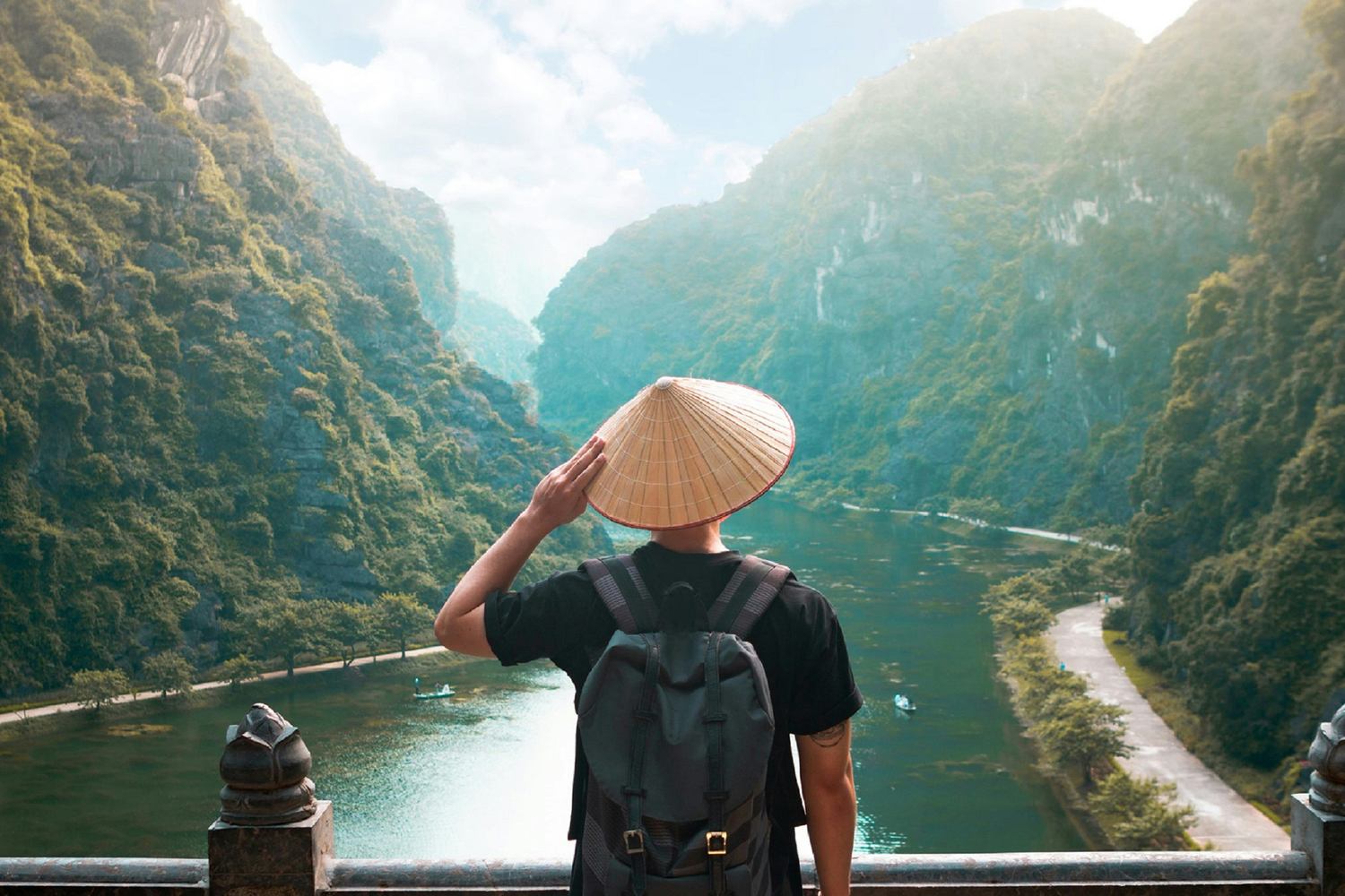 Viaggiatore di spalle con cappello conico vietnamita ammira la valle carsica di Trang An in Vietnam