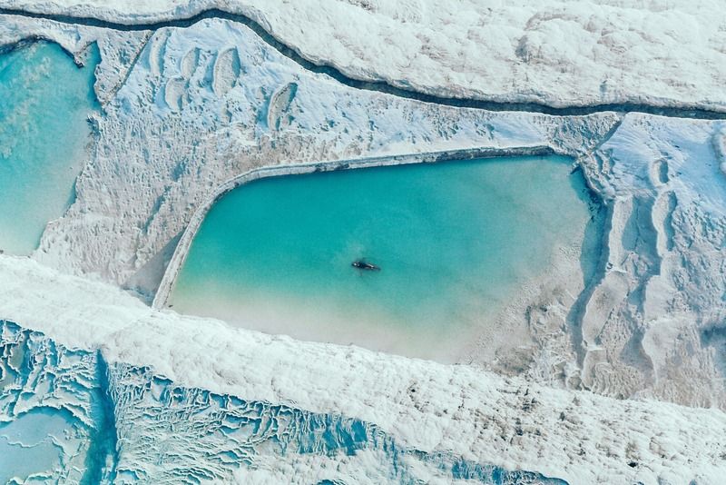 Vista aerea delle piscine turchesi di travertino a Pamukkale con una persona che nuota