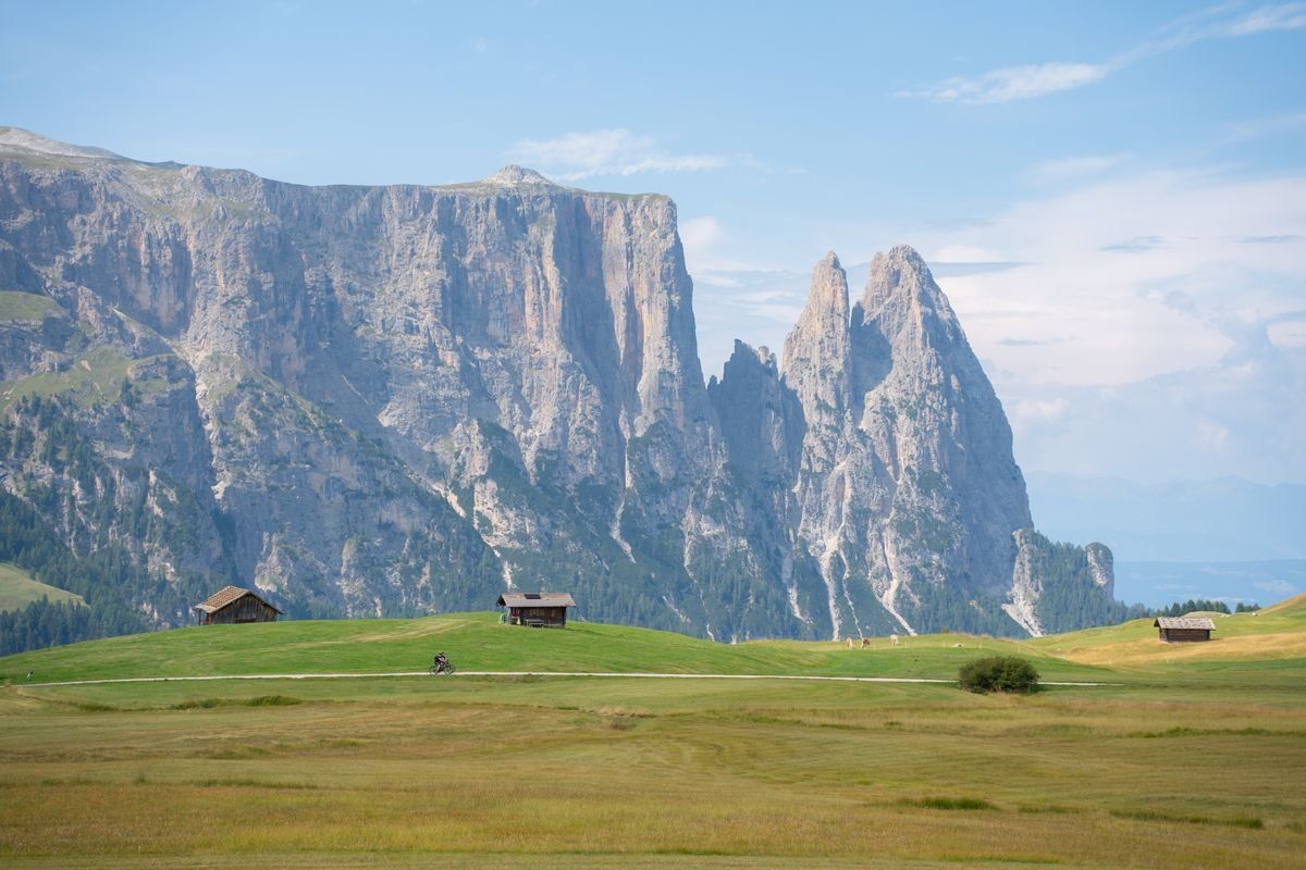 Baite sull'altopiano dell'Alpe di Siusi con cime dolomitiche sotto un cielo sereno