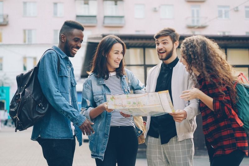 Gruppo di amici sorridenti consulta una mappa cittadina durante un viaggio in gruppo