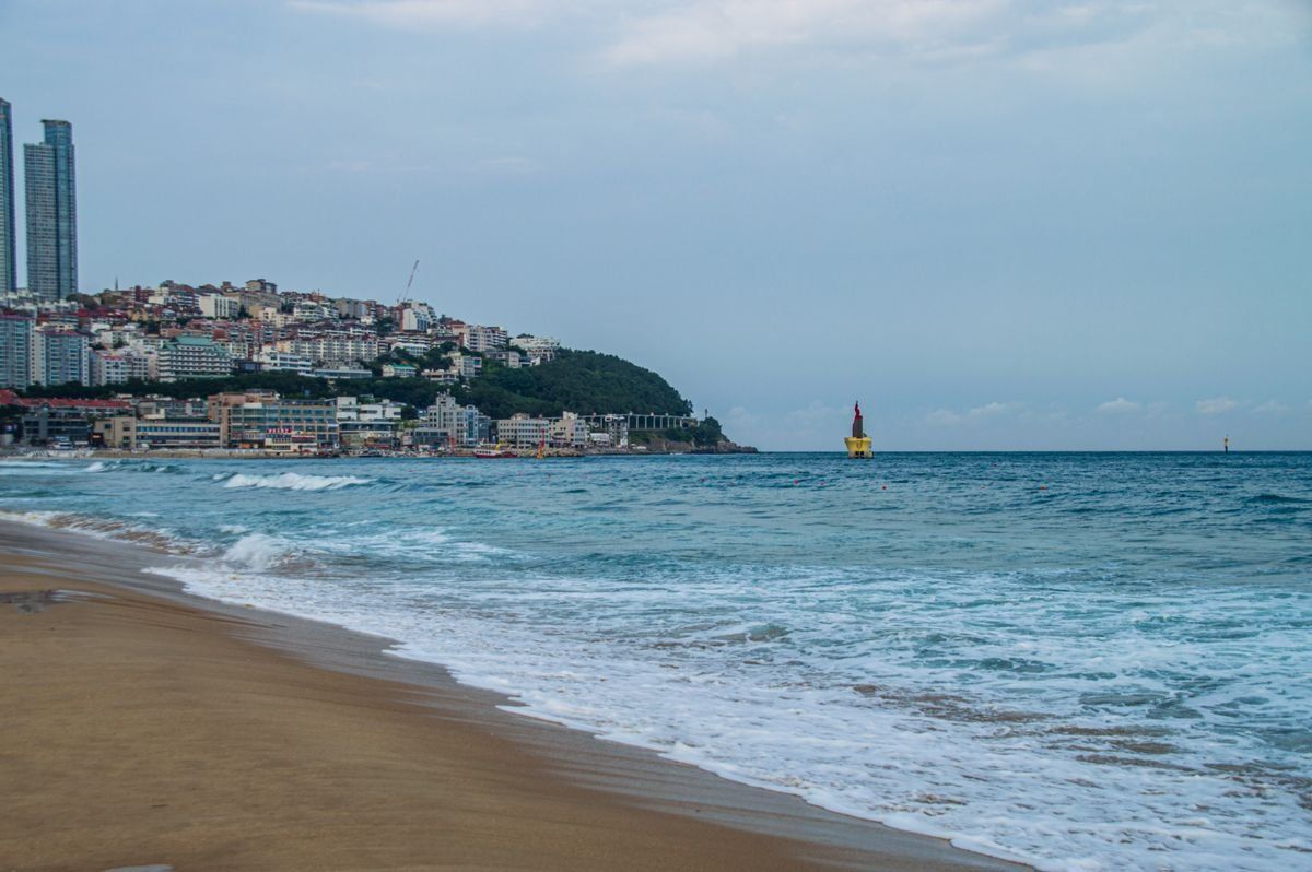 Litorale di Haeundae con onde leggere, grattacieli sulla costa e boa in mare