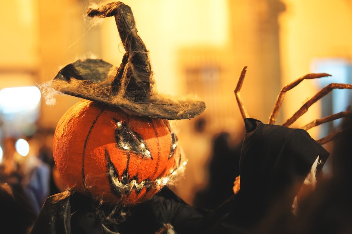 Maschera a forma di zucca con cappello da strega accanto a una figura in costume scuro