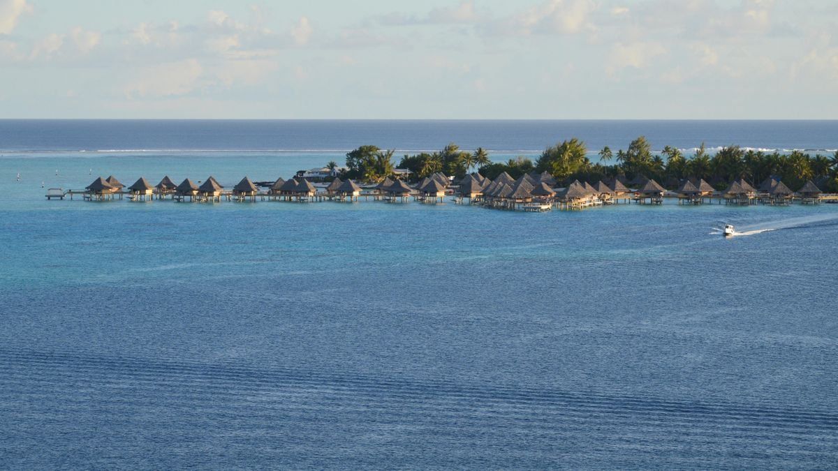 Resort su isolotto con bungalow sull’acqua e motoscafo nella laguna blu