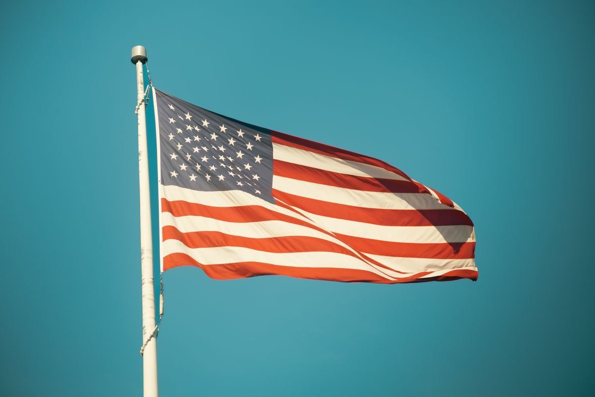 Bandiera americana che sventola su un pennone contro il cielo azzurro