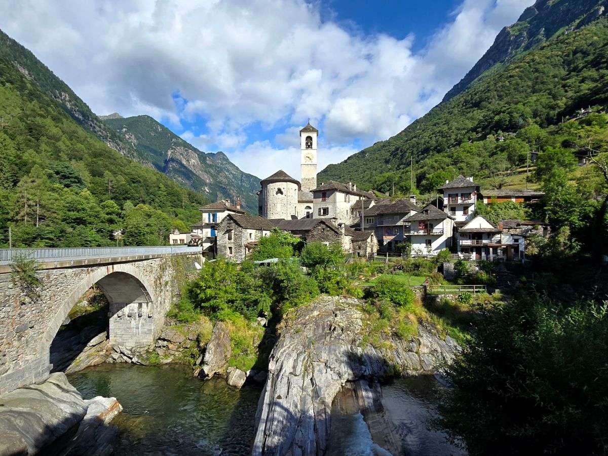 Borgo di montagna con ponte in pietra, chiesa e case tra le Alpi svizzere