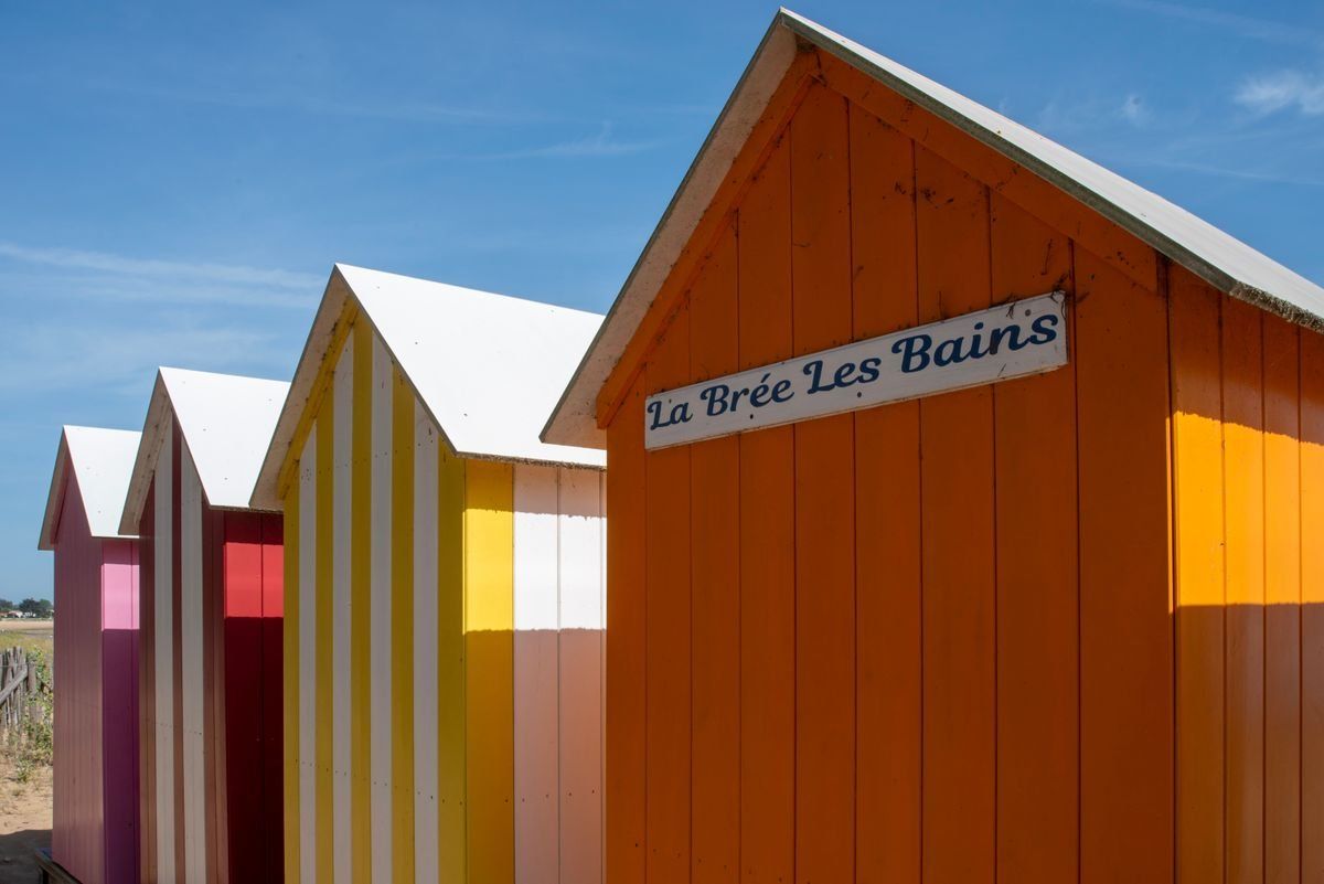 Cabine da spiaggia a righe colorate sotto il cielo azzurro a La Brée Les Bains