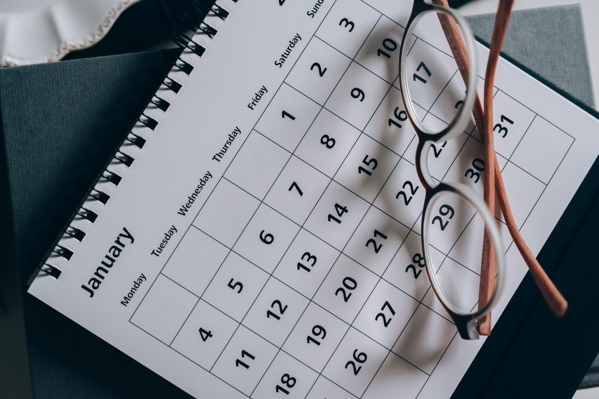Occhiali appoggiati su un calendario di gennaio aperto su un tavolo
