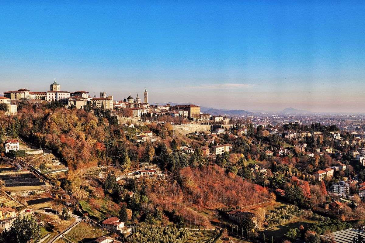 Panorama di Bergamo dall'alto con città storica sulla collina e alberi dai colori autunnali