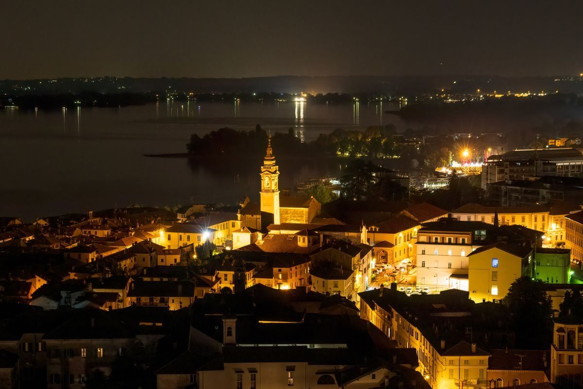 Panorama notturno di Angera con campanile illuminato, case e lago sullo sfondo