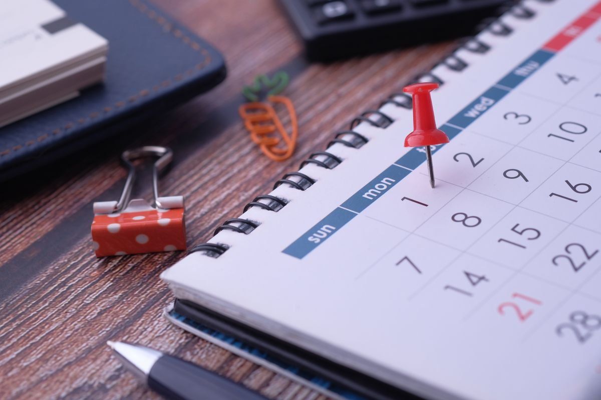Puntina rossa su calendario da scrivania accanto a penna e fermaglio