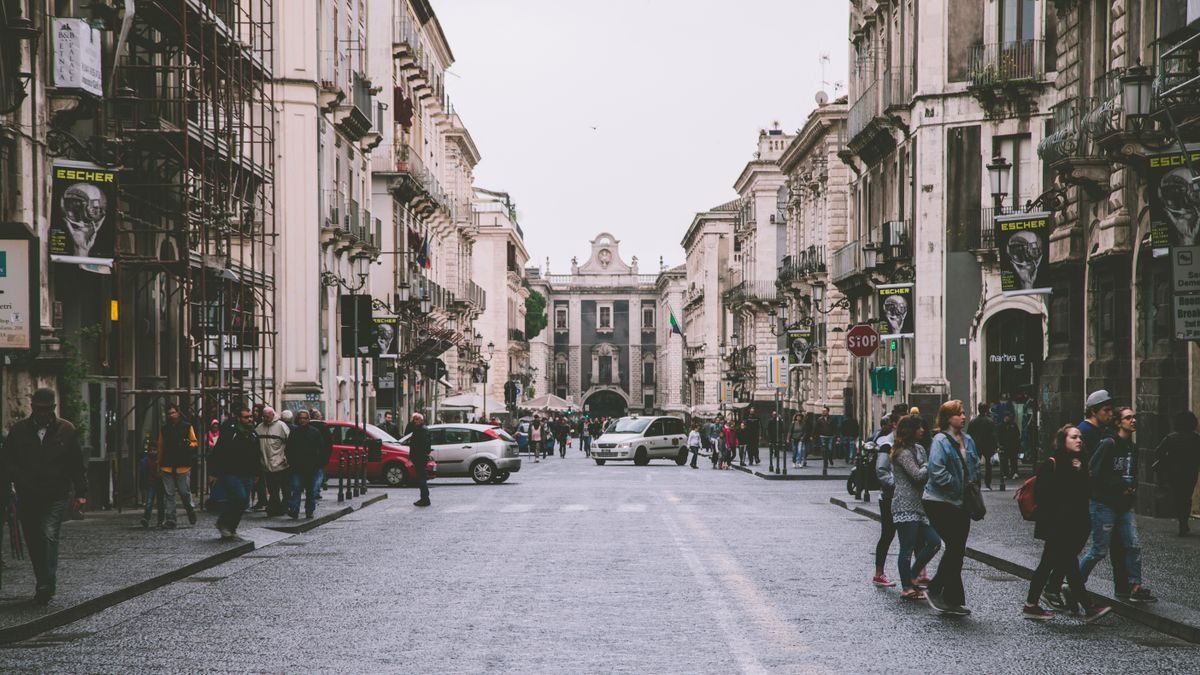 Ampia strada del centro con pedoni, auto e palazzi storici ai lati