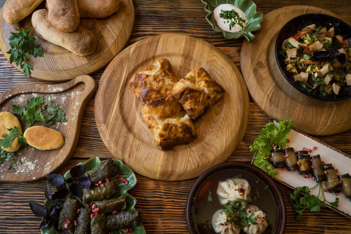 Assortimento di piatti georgiani su tavolo di legno con erbe fresche