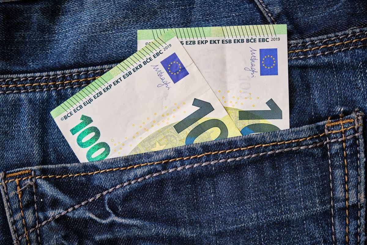 Banconote in euro che sporgono dalla tasca di un paio di jeans