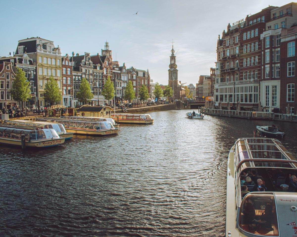 Canale di Amsterdam con battelli turistici, edifici storici e torre della Westerkerk sullo sfondo