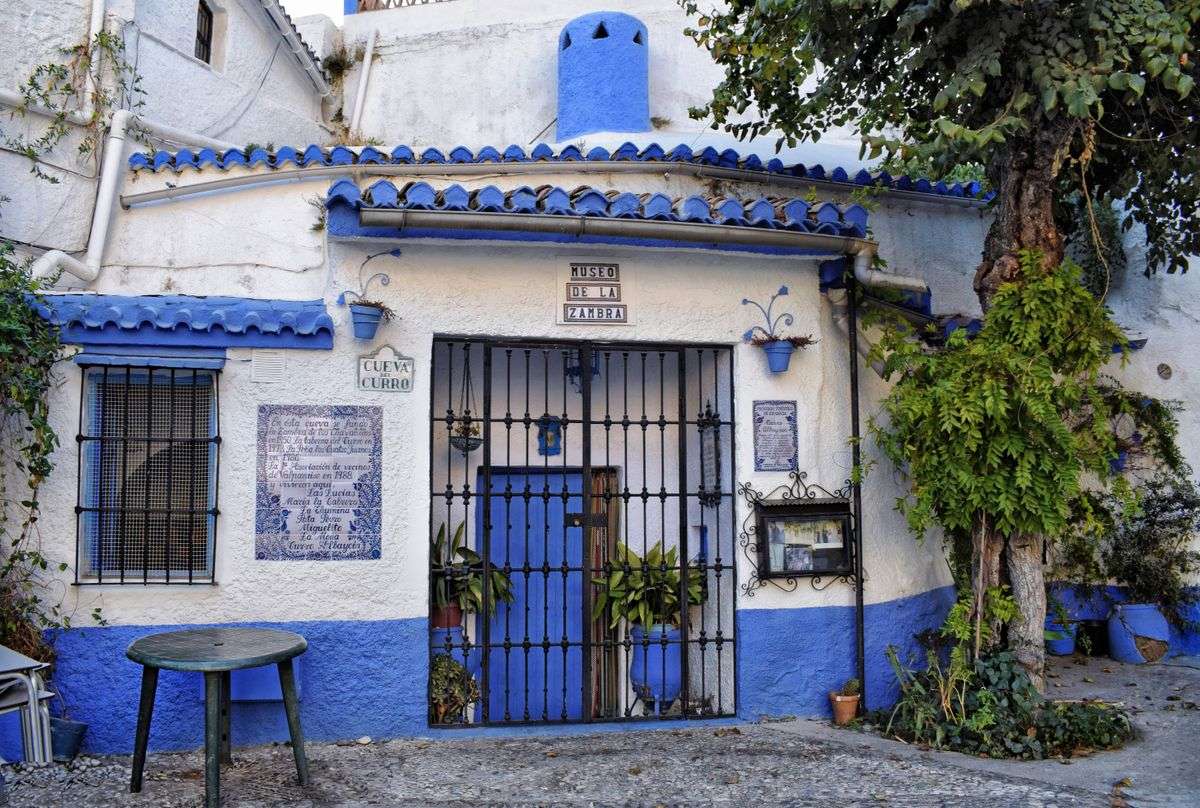 Facciata bianca e blu del Museo de la Zambra con porta in ferro e targhe decorative