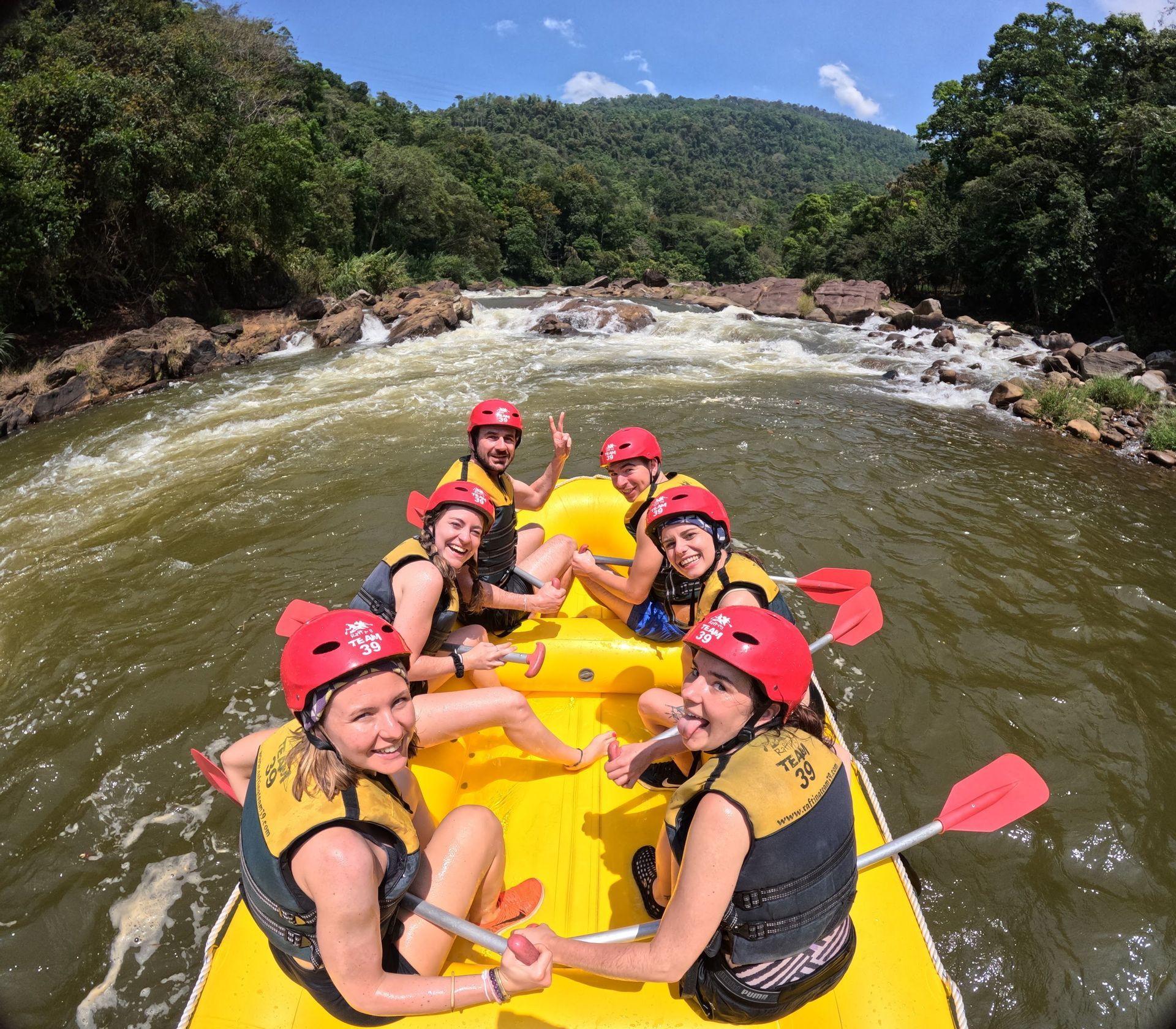 Un gruppo WeRoad con caschi rossi e giubbotti di salvataggio sorride per una foto su un gommone giallo durante un'escursione di rafting.