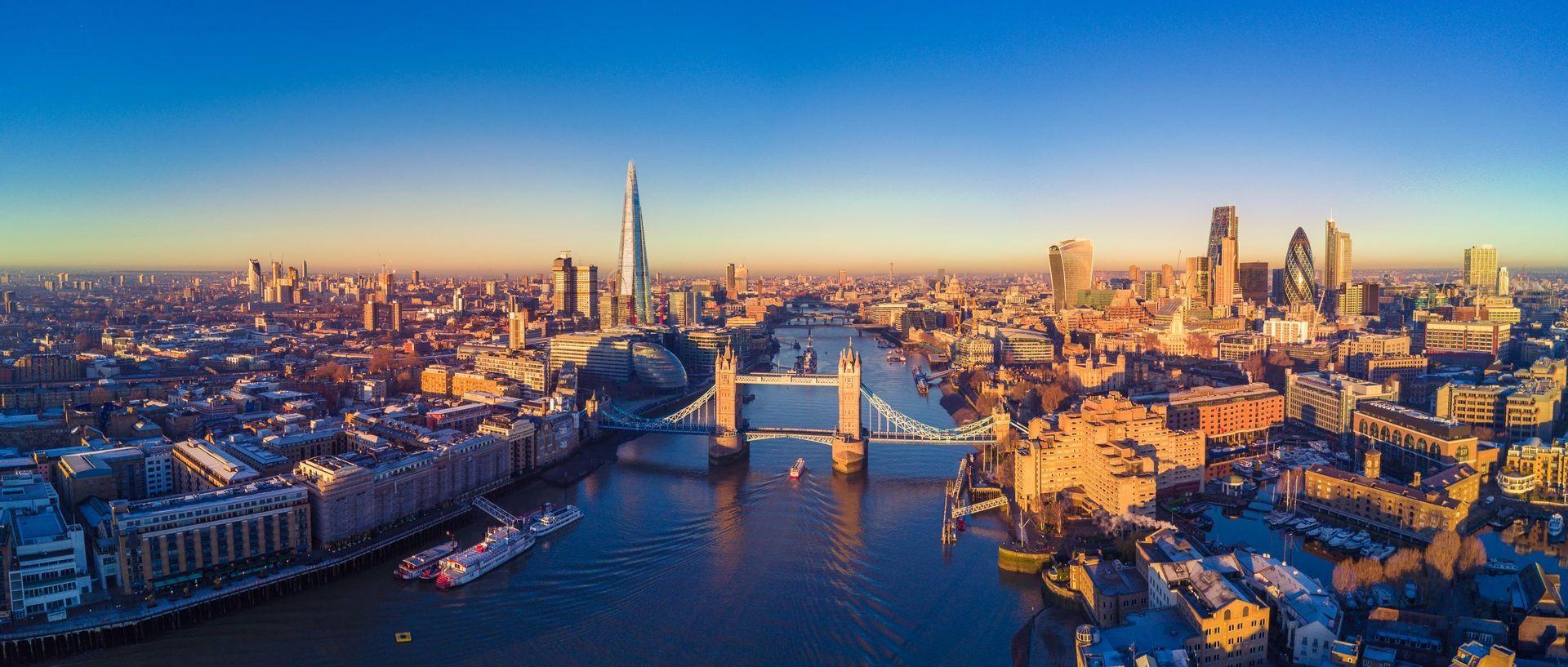 Panorama aereo dello skyline di Londra con il Tamigi, il Tower Bridge e altri grattacieli all'alba.