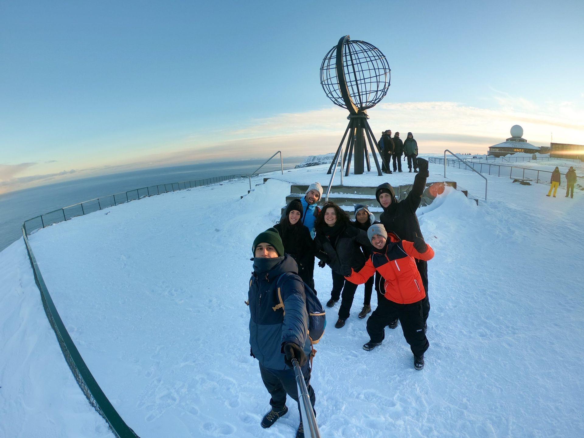 Fatti un viaggio avventura per festeggiare il Natale in giro per il mondo! Fatti un WeRoad! Foto di gruppo a Capo Nord in Norvegia - WeRoad