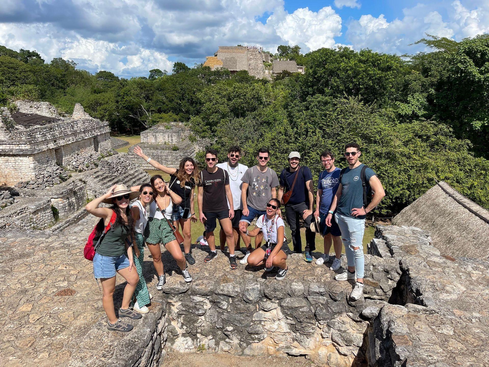 Un gruppo WeRoad si fa fotografare su antiche rovine, con una giungla fitta e un altro tempio sullo sfondo.