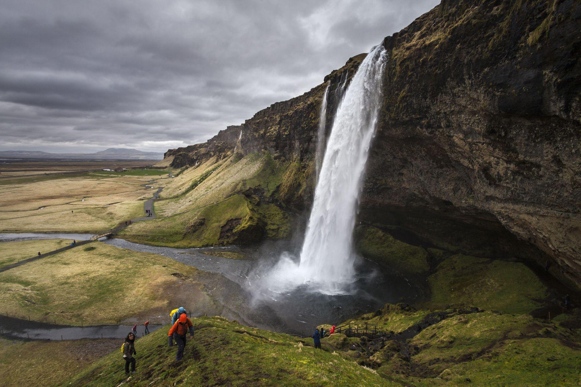 Un gruppo WeRoad in escursione su una verde collina che sovrasta una grande cascata, la quale precipita da una parete rocciosa in un'ampia valle.