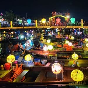 Un río de noche, lleno de pequeñas embarcaciones transportando personas e iluminado por coloridas linternas de papel.