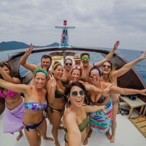 Un viaje en grupo de WeRoad con personas en traje de baño posando para una selfie en la cubierta de un barco en el mar.