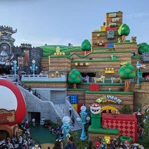 Una vista panoramica del parco a tema Super Nintendo World, che mostra il Castello di Bowser, colline terrazzate e folle di visitatori.
