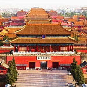 Una vista dall'alto di un complesso di palazzi tradizionali cinesi con i caratteristici tetti di tegole arancioni, mura rosse e un portone principale.