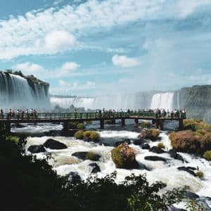 Un viaggio di gruppo WeRoad su una piattaforma panoramica sopra un fiume impetuoso, con una vista mozzafiato su cascate imponenti.