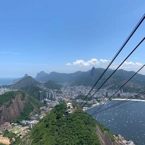 Vista aérea desde un teleférico de una ciudad costera rodeada de montañas verdes y una bahía con muchos barcos.